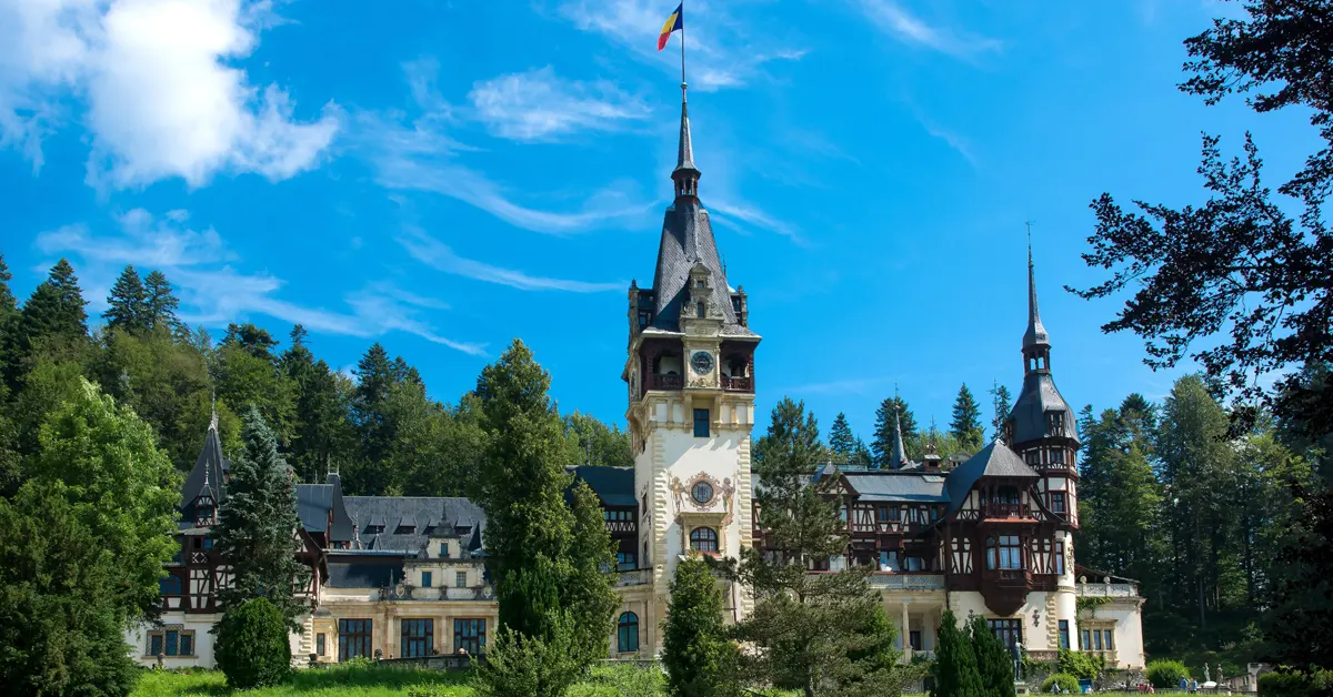 The Peles Castle surrounded by green trees.