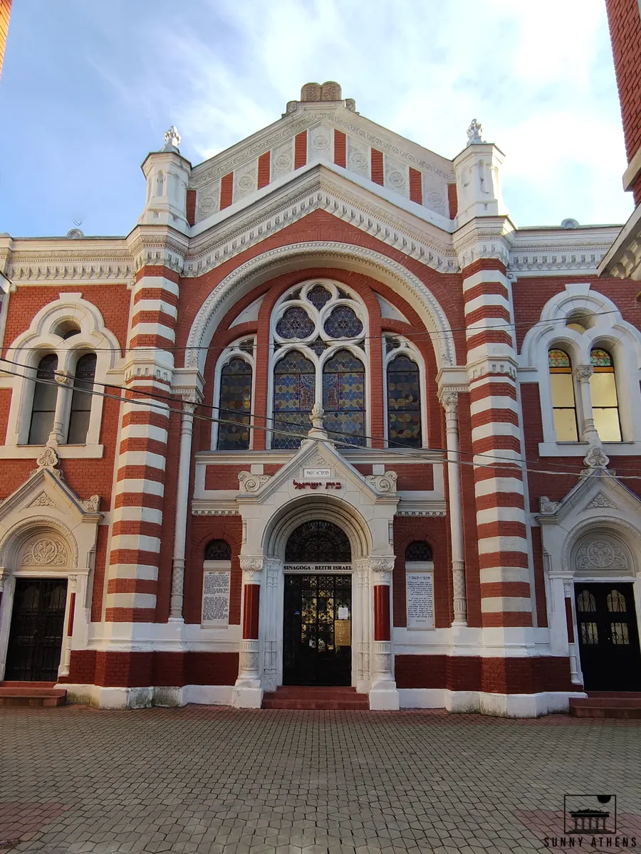 Unique Experiences in Brasov: The Beth Israel Synagogue facade, with red and white bricks, and colorful windows.