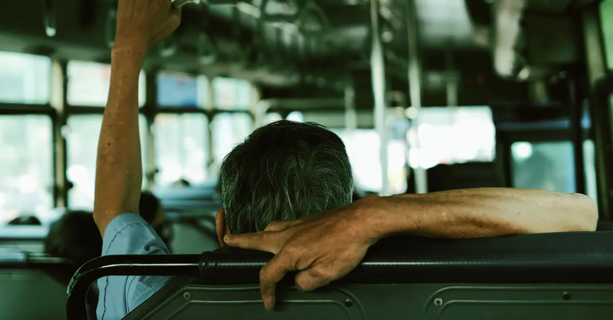 An elderly man sits on the bus.