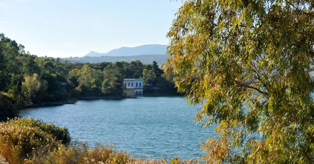 A historic building at Lake Marathon nestled among dense trees, and distant hills on the horizon.