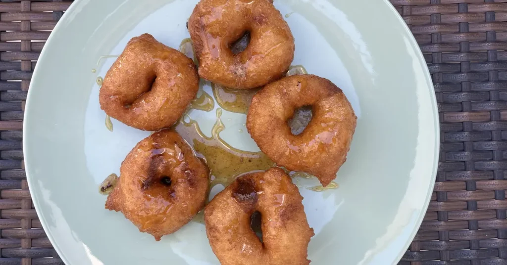 A plate of golden-brown loukoumades, the traditional Greek honey-drenched doughnuts.