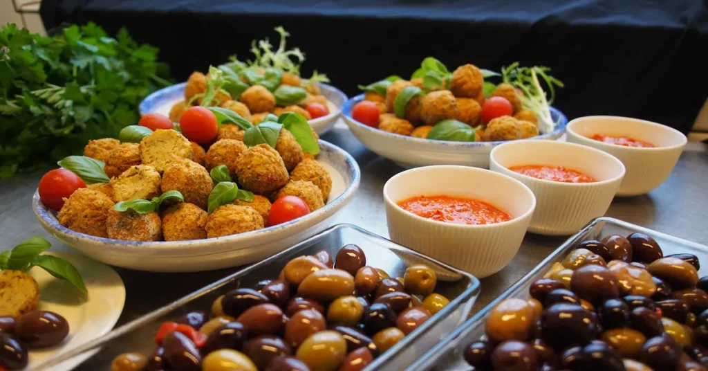 Local food in Athens: A plate of crispy snacks with basil leaves and little tomatoes, bowls of tomato sauce, and a tray of different kinds of olives. This is called 'meze' in Greek food.