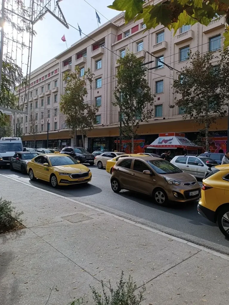 The large building of shopping mall Attica in the centre of Athens, with a lot of cars in front of it stuck in the traffic.