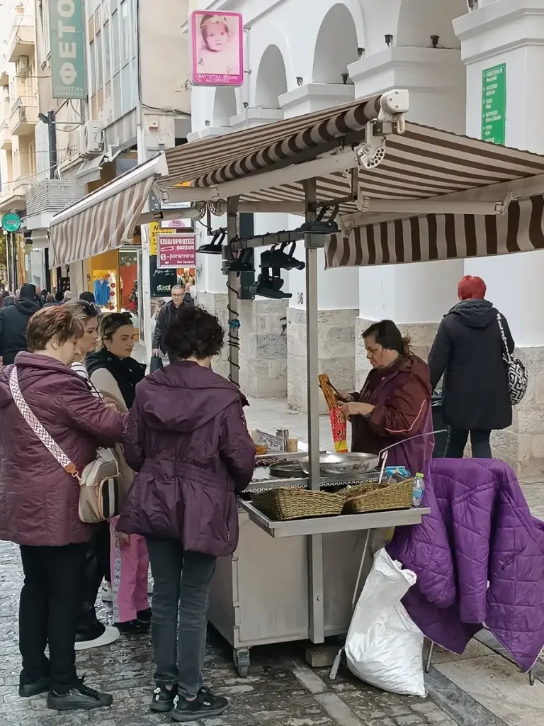 Women buying roasted chestnuts from a street vendor at Ermou Street. It's one of the best experiences you can have in the local markets in Athens.