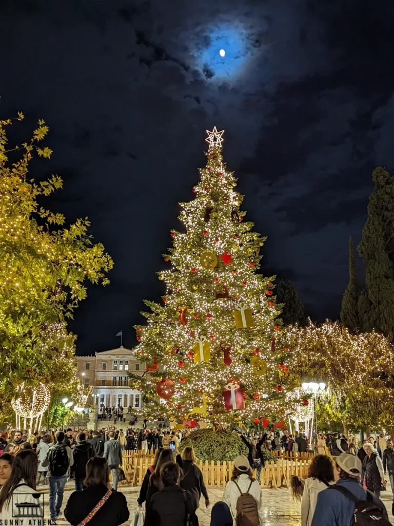 Festive Christmas tree lighting up the night in the Syntagma with a full moon above.