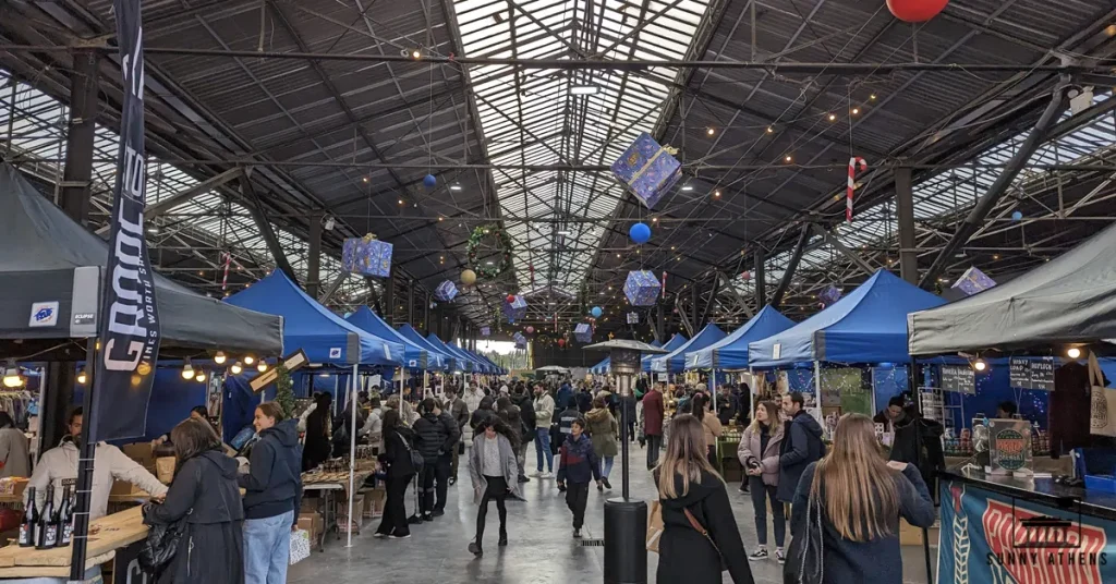 Crowded Christmas market inside the Old Depot of OSY in central Athens.