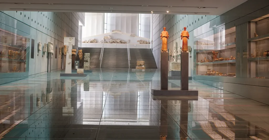 Winter in Athens: The Gallery of the Slopes of the Acropolis Museum featuring artifacts on shelves and two statues in the foreground.