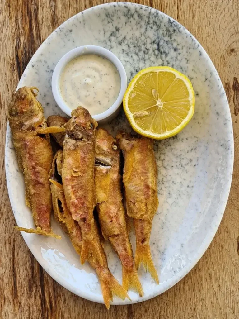 Fresh fried fish served on a small plate in a traditional Greek tavern.