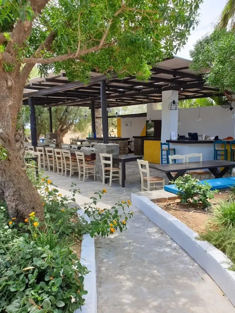 The cozy beach bar of Faragas shaded by lush trees, offering a tranquil spot for visitors to relax.