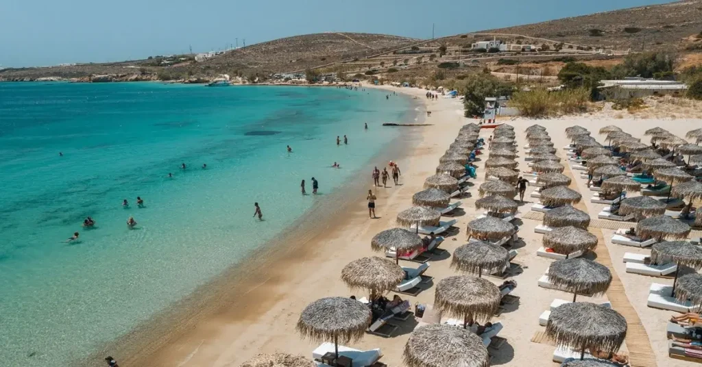 People sunbathing and swimming at the sandy beach of Marcelo in Paros Greece.