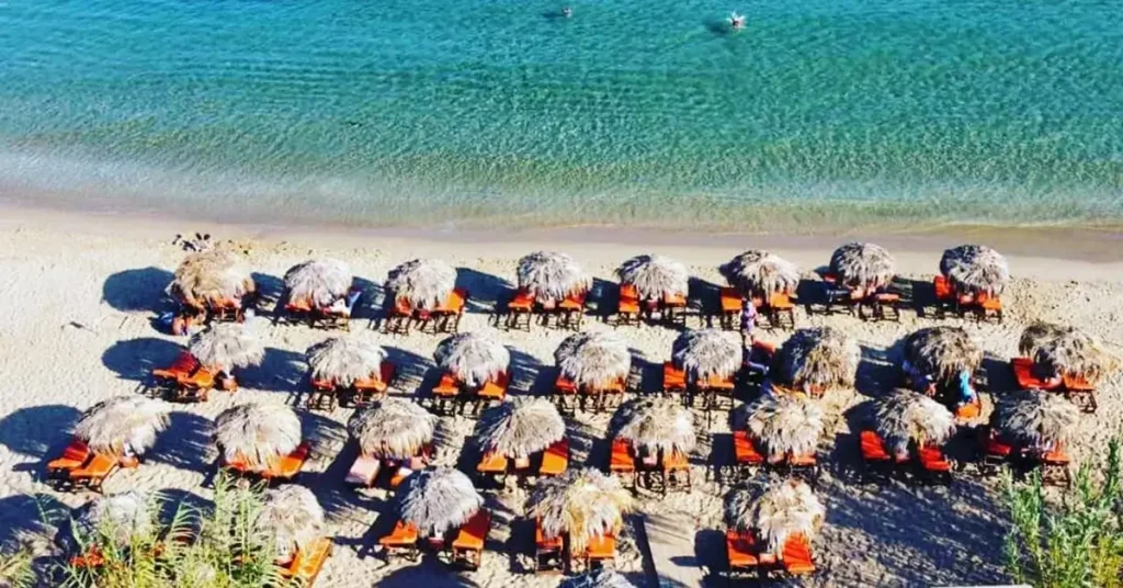 Sunbeds lined up in the shore of the amazing Golden Beach in Paros Greece.