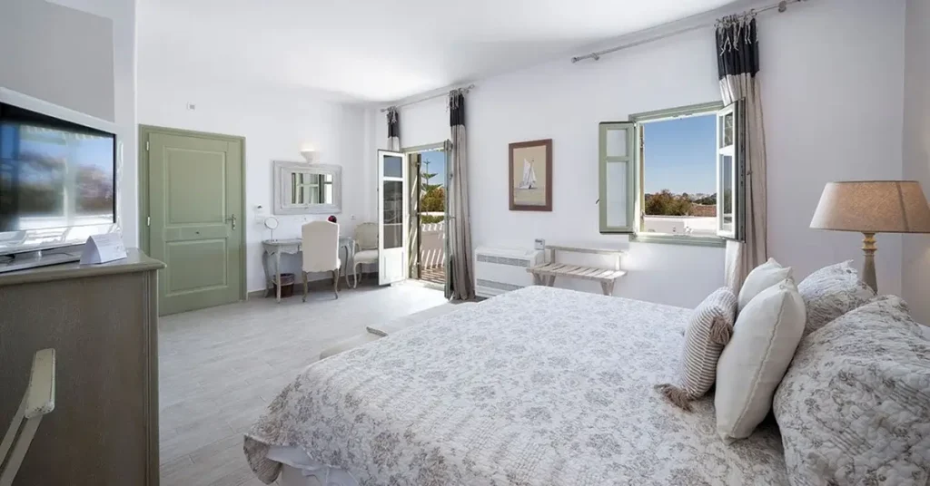 A room with open windows offering a view of Paros at Saint Andrea Resort.