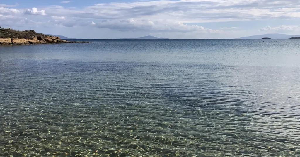 Calm, transparent waters at Punda Beach with a view of distant islands and a clear blue sky.