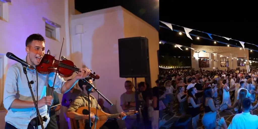 An enthusiastic violinist performing live at a traditional Greek fest in Paros, with a crowd of people dancing hand in hand.