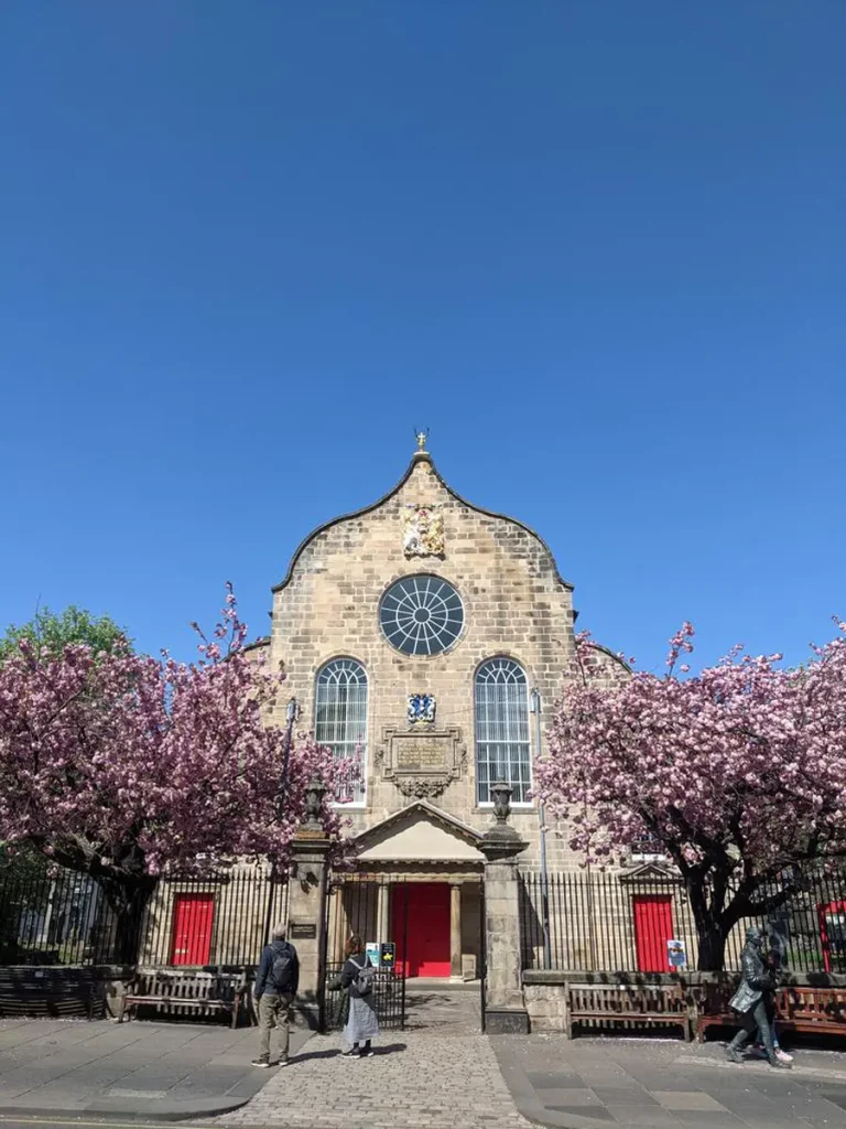 Canongate Kirk under the sunlight and surrounded by blossoming trees.