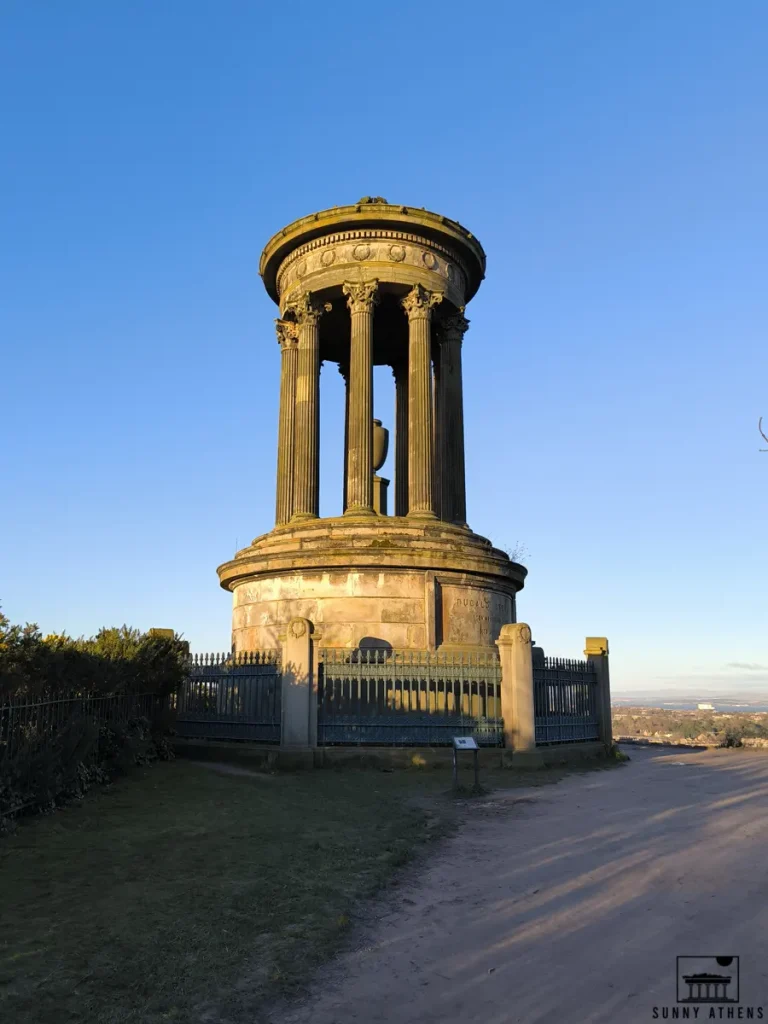 The iconic Dugald Stewart Monument on Calton Hill, notable example of Neoclassical architecture, and panoramic view of Edinburgh in the background.