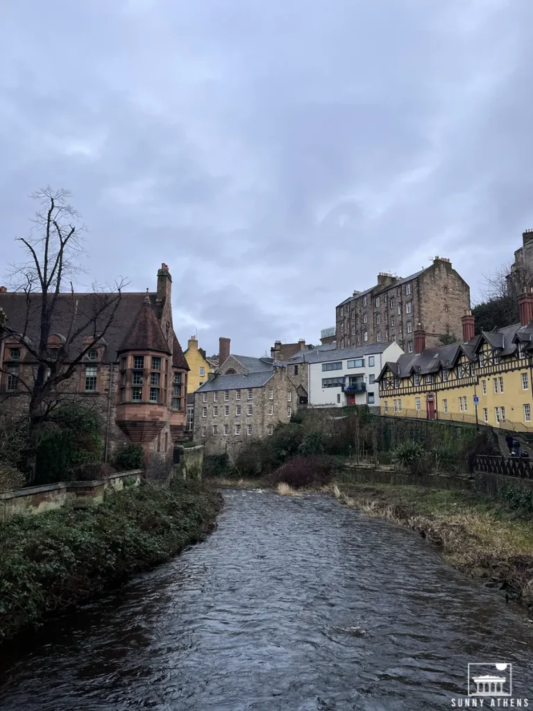 The serene Water of Leith Walkway, flowing past historic buildings under a cloudy sky.