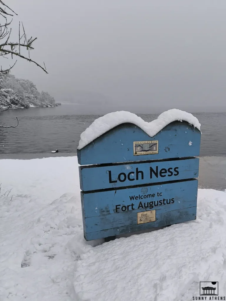 A snowy, wooden welcome sign for Loch Ness at Fort Augustus.