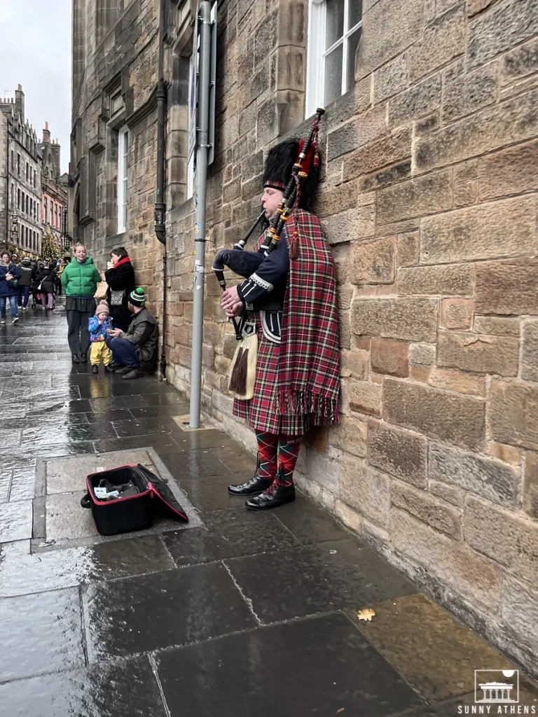 4 days in Edinburgh itinerary: A bagpiper in traditional Scottish attire playing on a wet city street.