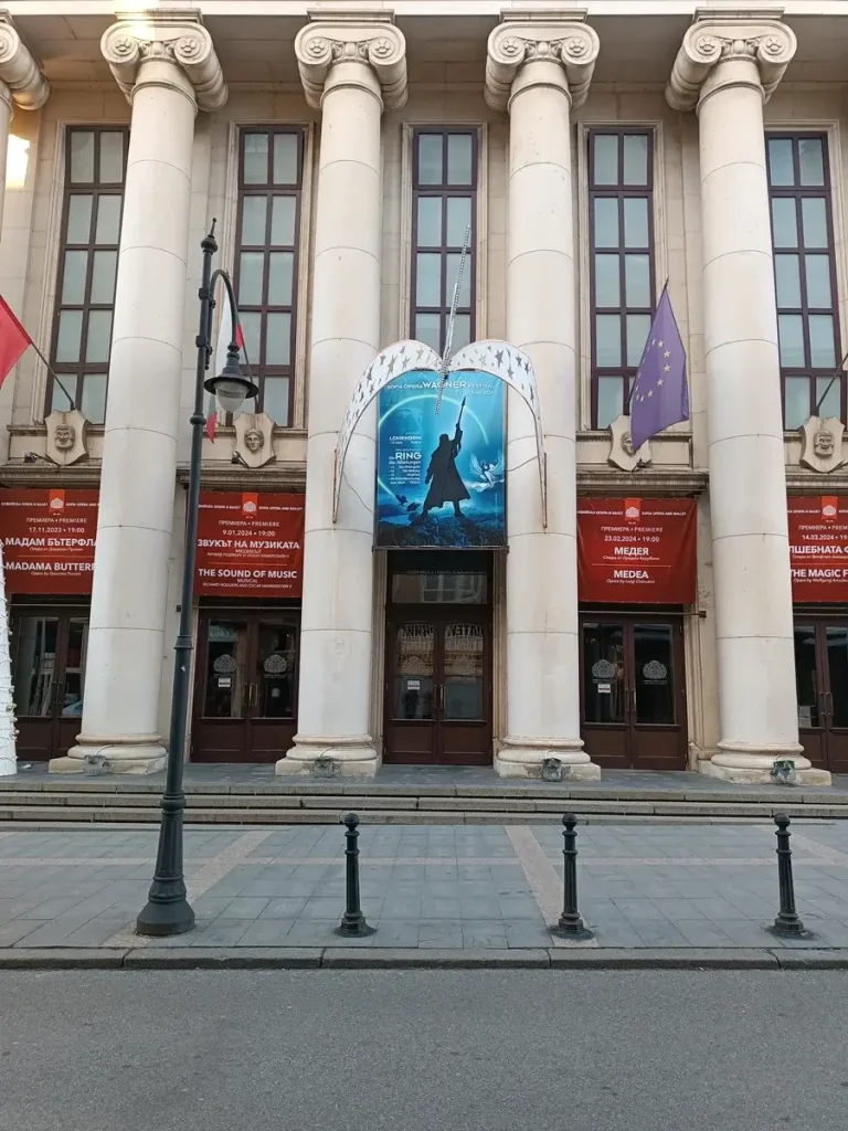 The entrance to Sofia Opera and Ballet House, featuring Greek Ionic-style columns and banners in Bulgarian.