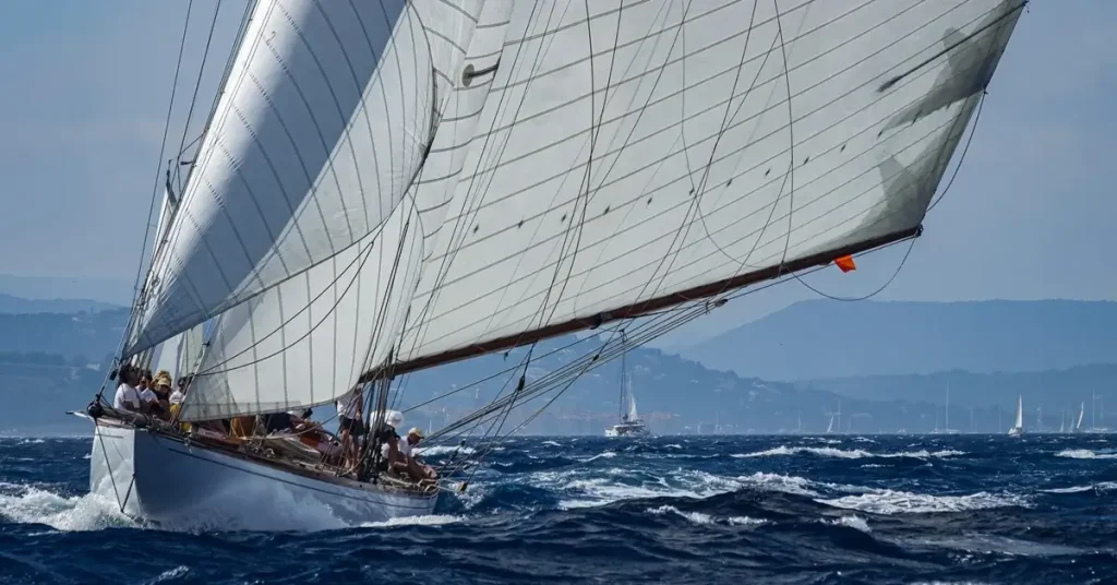 A sailing yacht with people on board is heeling in the blue waters of the Aegean sea at Paros Greece.