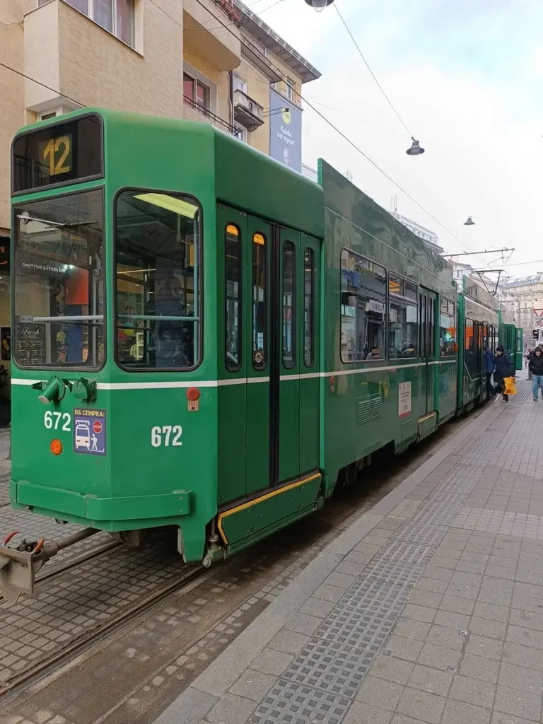 Passengers boarding a vintage green tram in the center of Sofia.