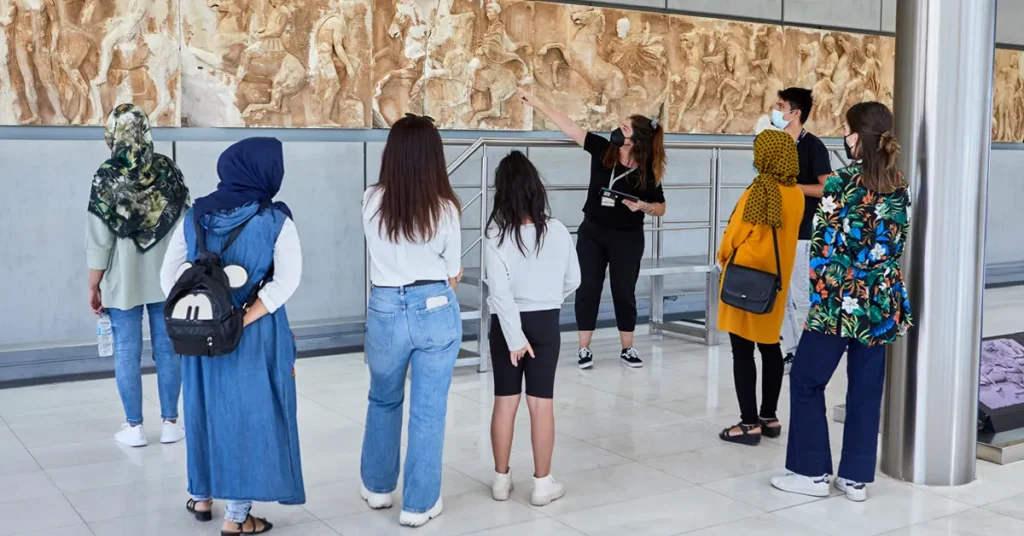 Visitors in a guided tour, exploring the ancient friezes at the Acropolis Museum.