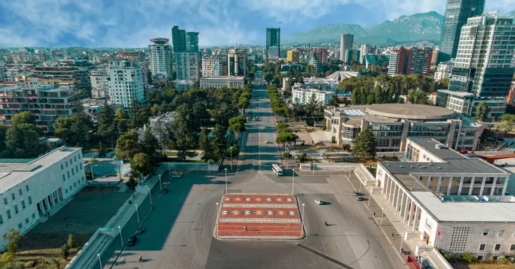 2 Days in Tirana itinerary: Panoramic aerial view of the city center, featuring skyscrapers, apartment buildings, and mountains in the background.