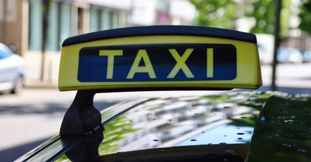 Close-up of a black and yellow taxi sign atop a car, signaling available services in the city.