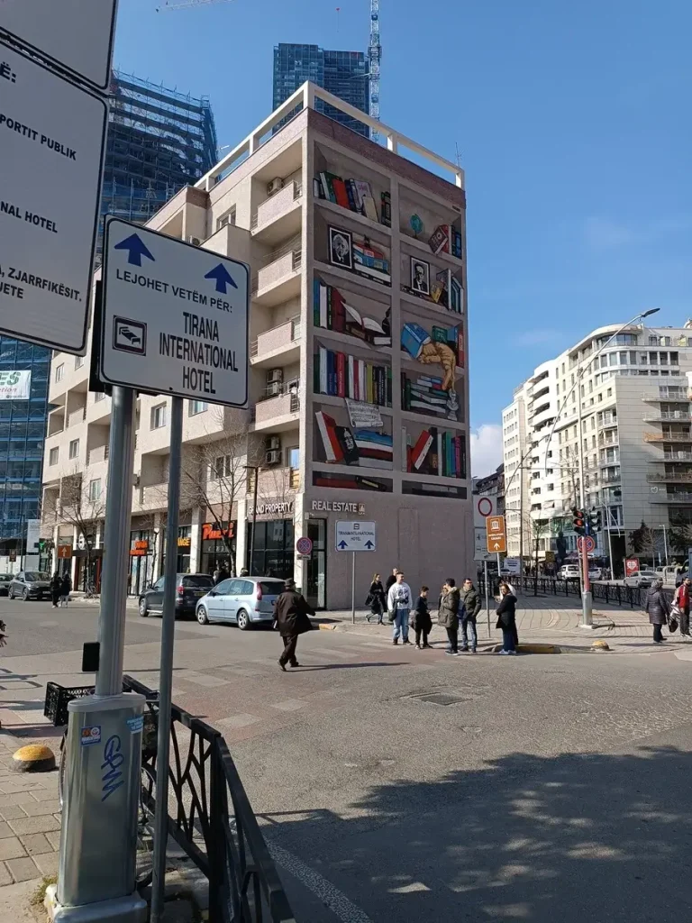 A refurbished building in the central square of Tirana, Albania, with impressive graffiti on the side depicting a home library.