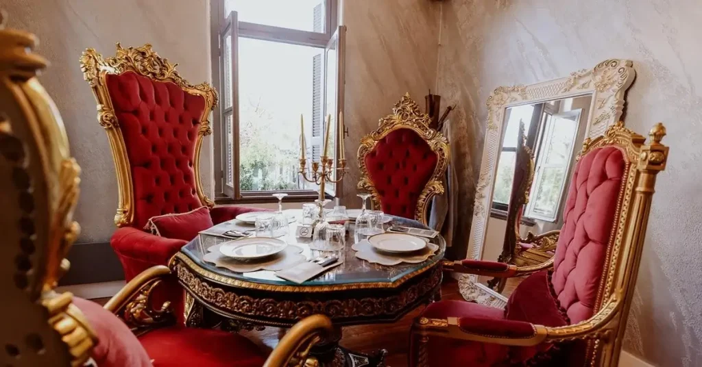 A luxurious dining setting with red velvet chairs around a table with elegant dinnerware, framed by a grand mirror at ROH restaurant in Plaka, Athens.