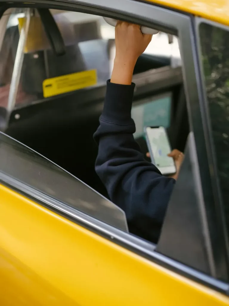 Bolt in Athens: A passenger holding a phone inside a yellow taxi.