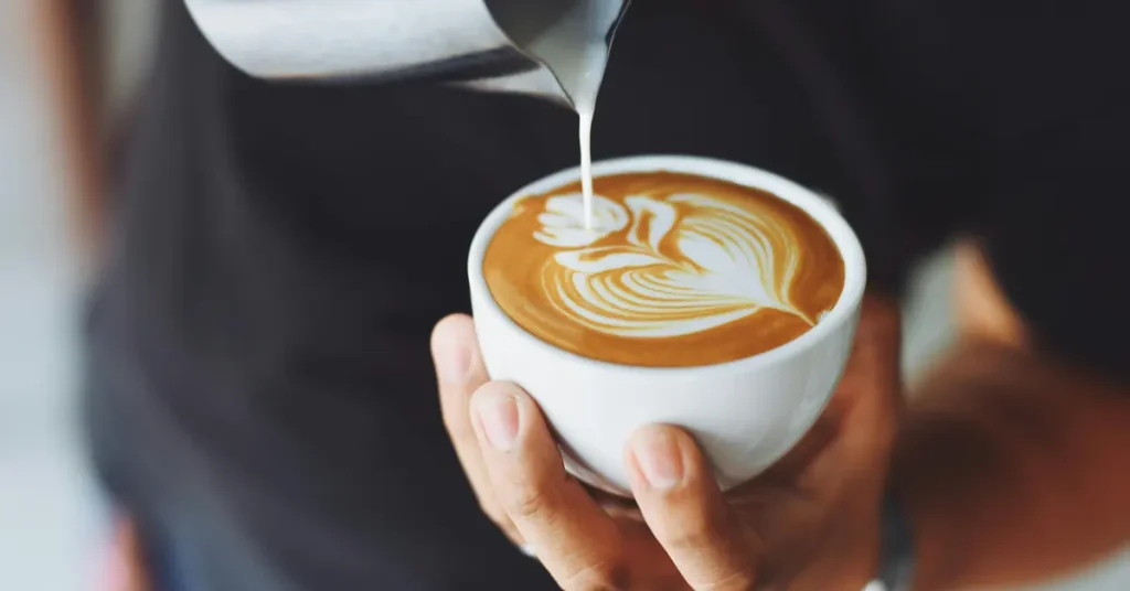 Pouring steamed milk into a cappuccino cup.